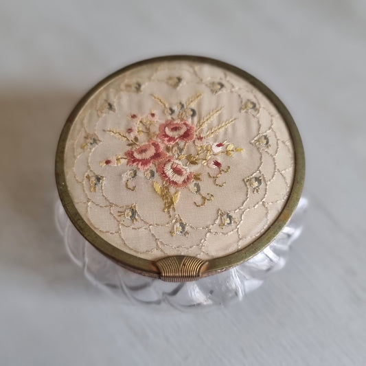 Vintage swirled clear glass jar with a gold-tone lid featuring embroidered pink roses on cream fabric