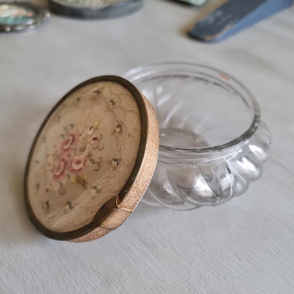 Vintage swirled clear glass jar with a gold-tone lid featuring embroidered pink roses on cream fabric