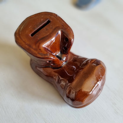 Glossy brown glazed pottery money box shaped like a lace-up boot with a coin slot in the top