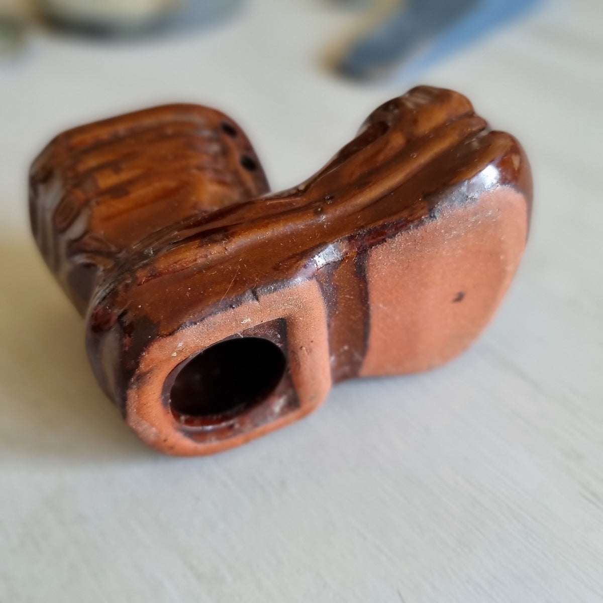 Glossy brown glazed pottery money box shaped like a lace-up boot with a coin slot in the top