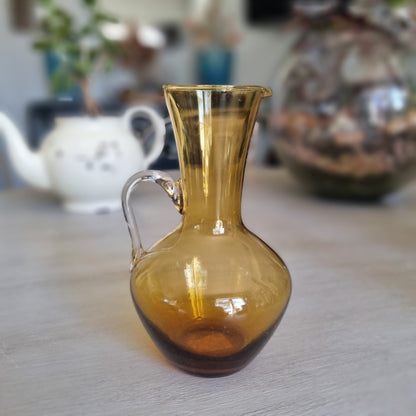 Vintage amber glass jug with a rounded body, pouring lip and clear glass handle
