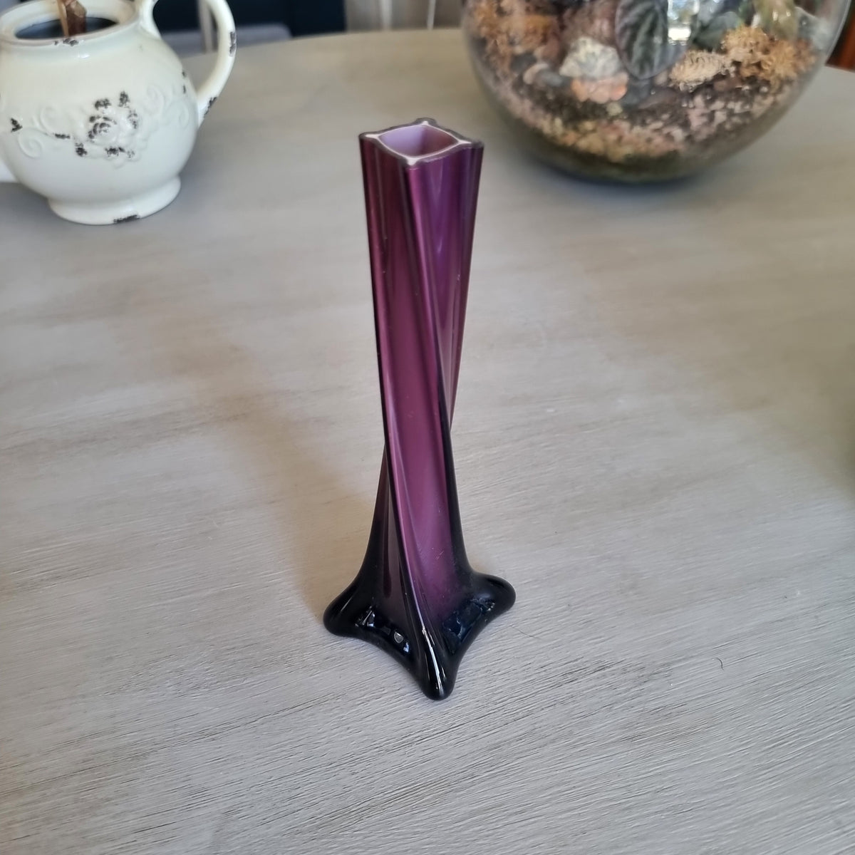 Vintage purple cased glass bud vase with white interior, twisted body and four-pointed foot