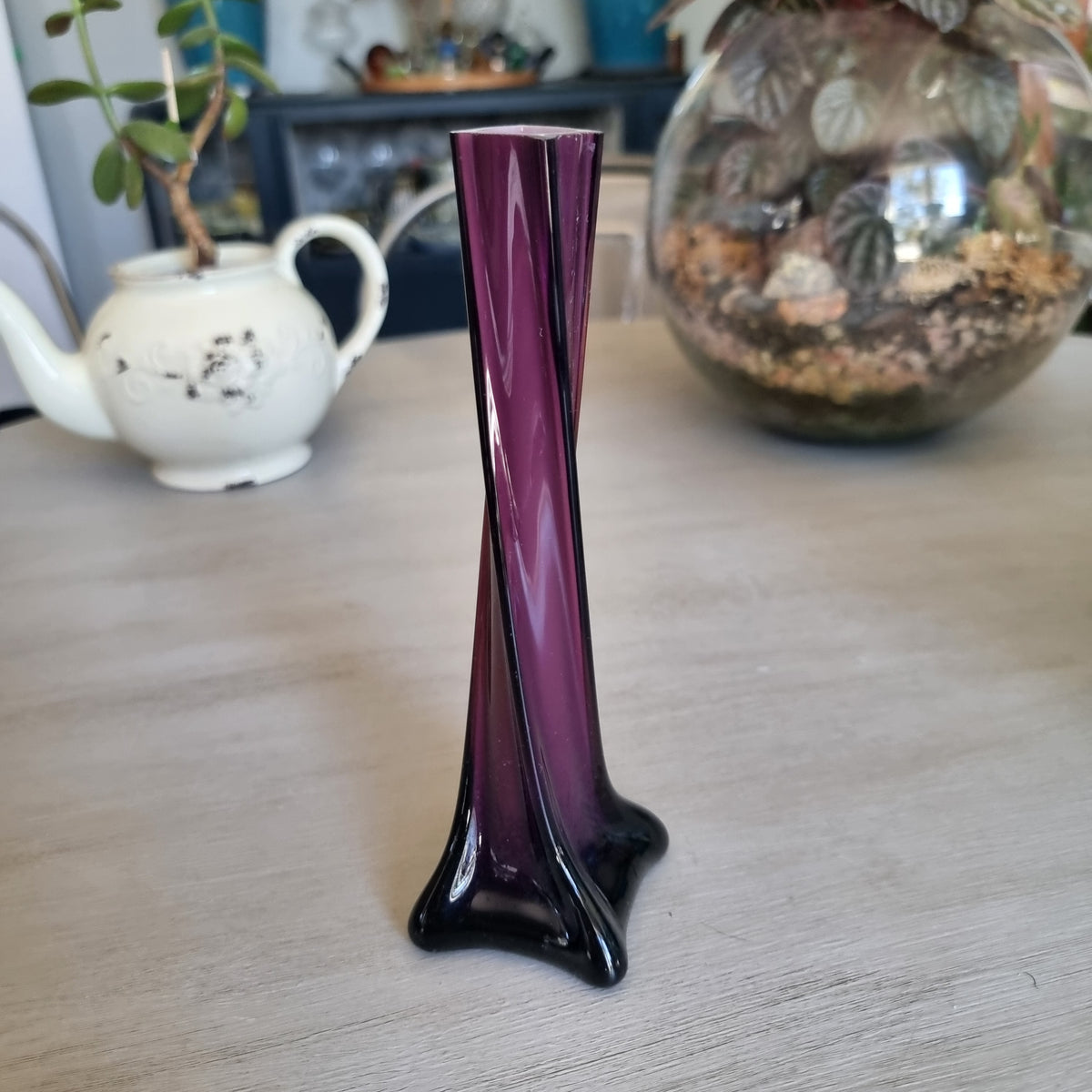 Vintage purple cased glass bud vase with white interior, twisted body and four-pointed foot