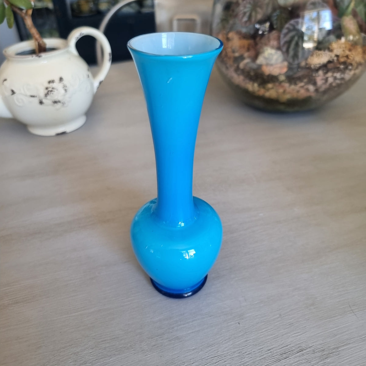 Vintage bright blue cased glass bud vase with a rounded body and tall trumpet neck