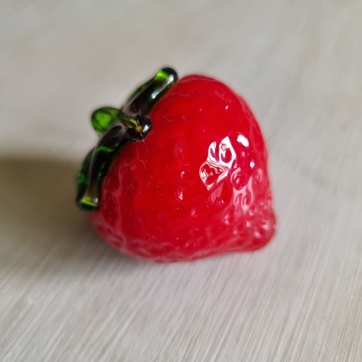Red glass strawberry ornament with green leaves