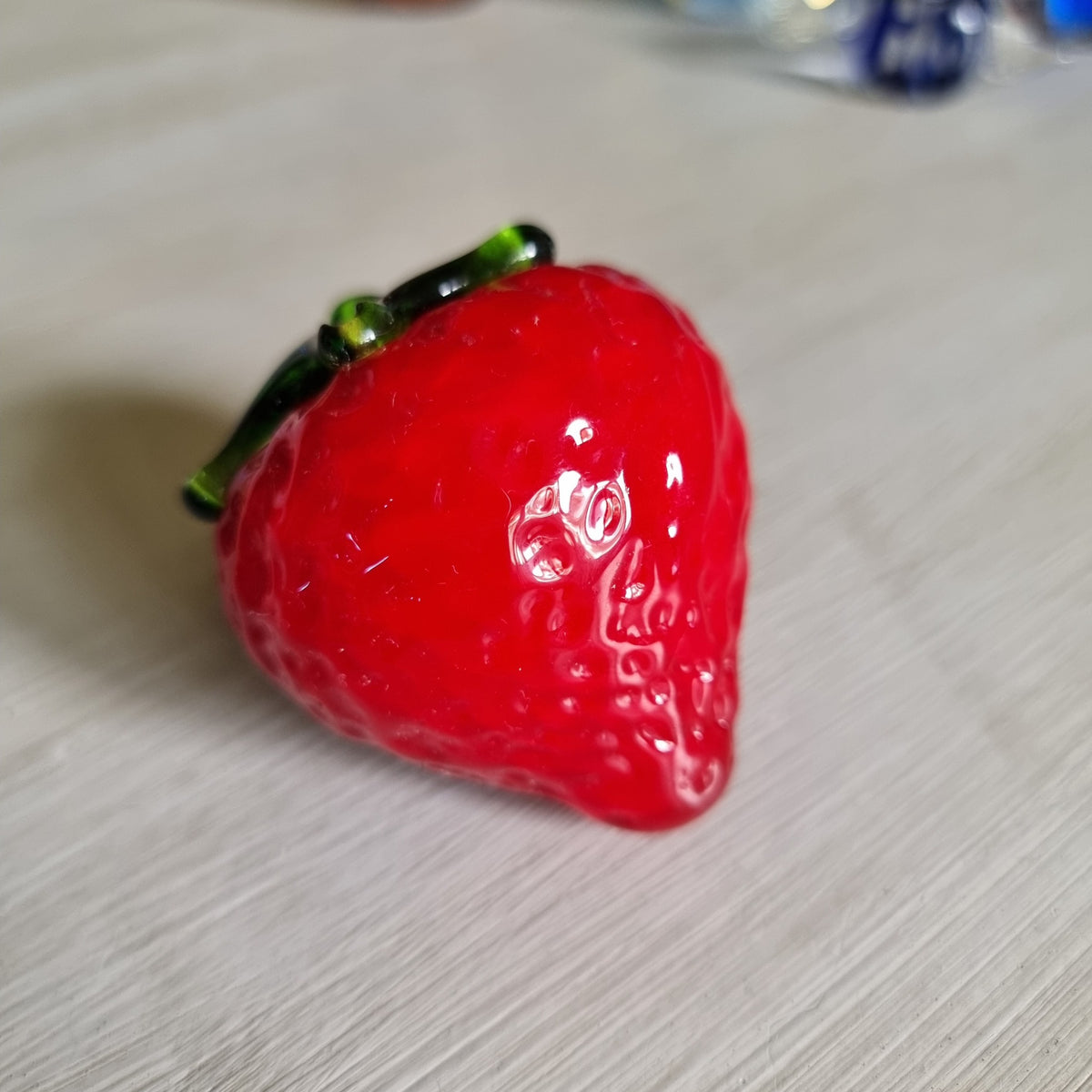 Red glass strawberry ornament with green leaves