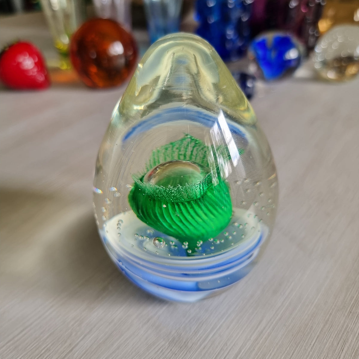 Large clear glass paperweight with blue and white swirls and green floral centre