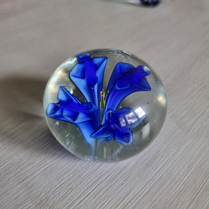 Clear glass paperweight with blue flower and yellow centre