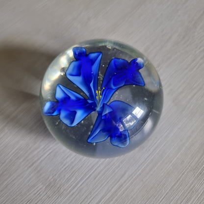 Clear glass paperweight with blue flower and yellow centre