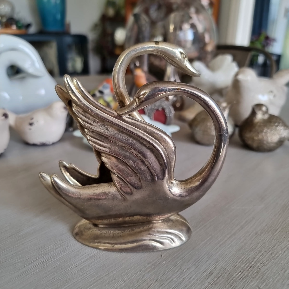 Silver swan napkin holder with sweeping feathered wings on a wave-shaped base