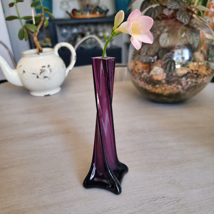 Vintage purple cased glass twisted bud vase holding a pale pink freesia